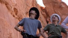 two students and their professor look up into a canyon