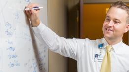 Alumni Patrick Halinsky uses a white board to map a process at a local hospital.