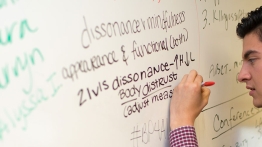 Student uses white board to explain psychology concepts.