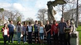 Students gather outside for a group photo in front of a winged statue