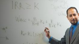 Professor teaching at a whiteboard facing a class