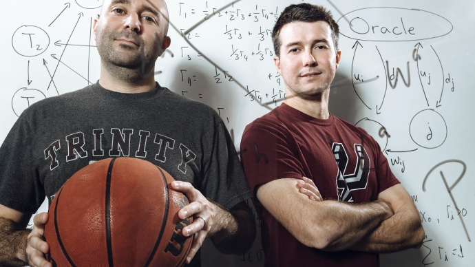 Mathematics professors Brian Miceli and Cabral Balreira behind a marked-up glass wall