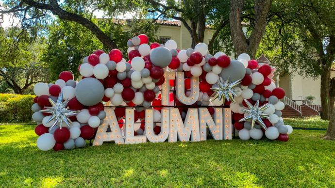 TU Alumni maroon and white balloons display on a lawn on campus