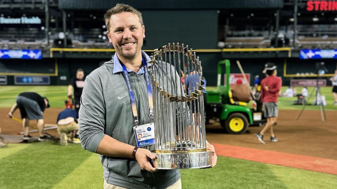 Stosh Hoover holding the World Series trophy while standing on a baseball field