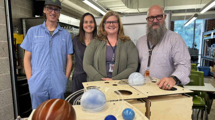 People standing over a scaled solar system model.