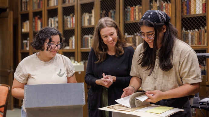 Three people stand over a table of books
