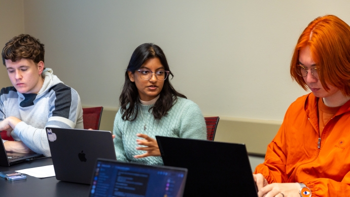 Gaya Rajamony (center) speaks in class while her classmates around her work on laptops