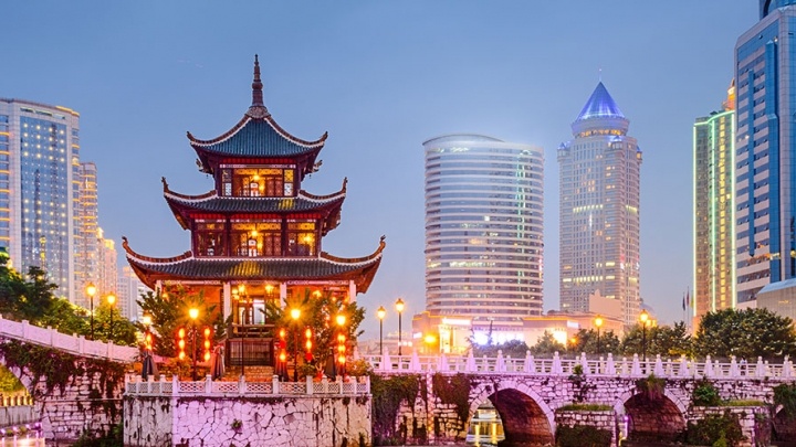 Traditional Chinese building on a river in front of modern cityscape