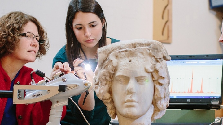Trinity professor and her student examine an ancient sculpted bust.
