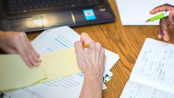Two students making making notes in multiple notebooks