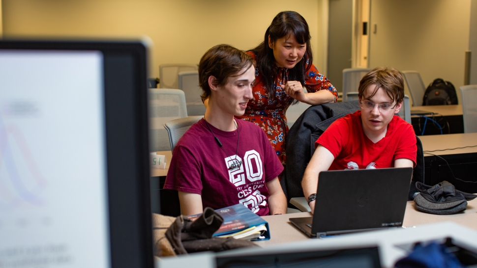 Hoa Nguyen and two students work at a laptop discussing math modeling.