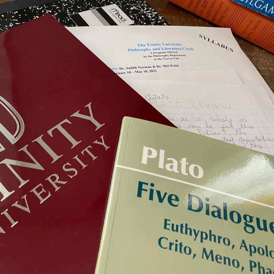 Plato's "Five Dialogues" lays on top of a Trinity folder and a hand-written essay