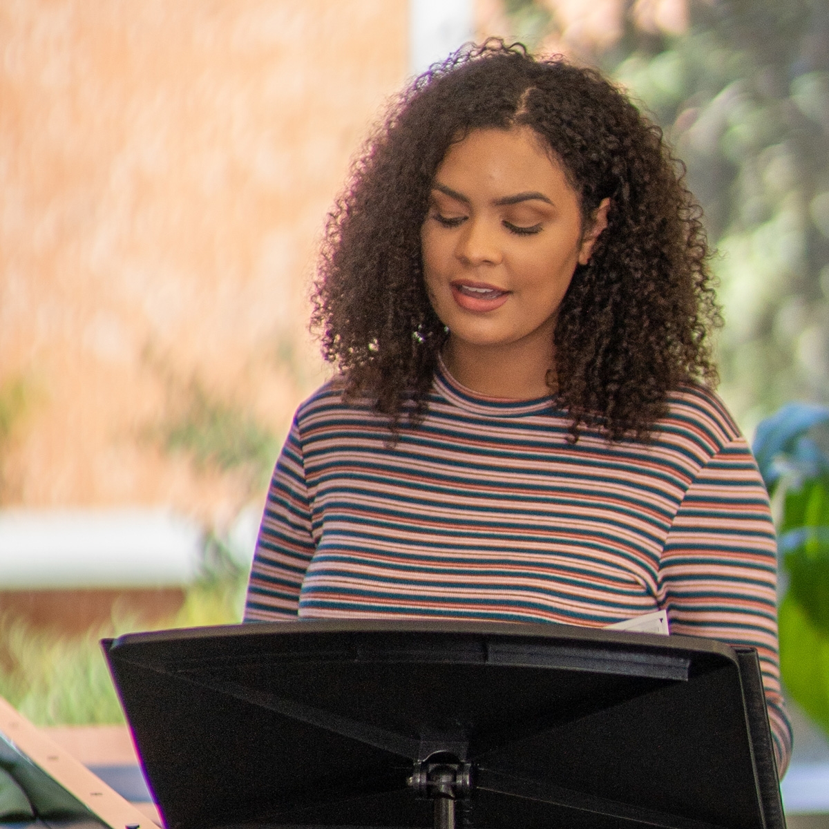 Caelia Marshall sings with sheet music on a music stand in a faculty rehearsal space