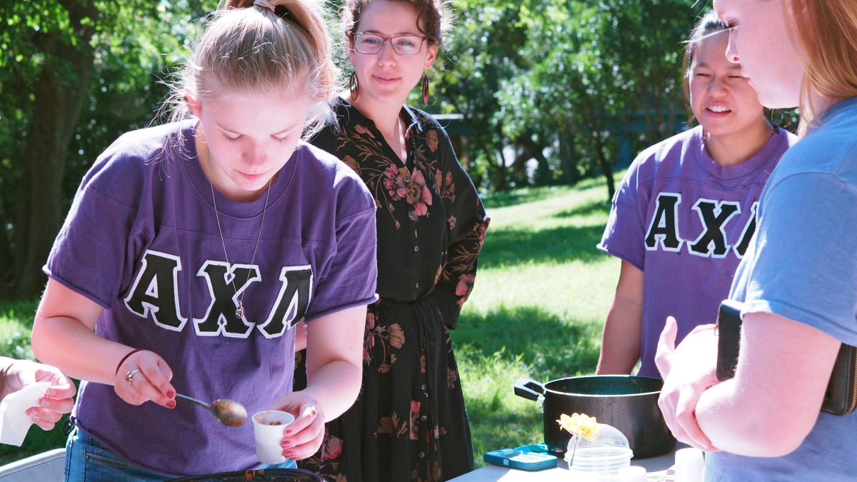 two sorority members serve chili from a crock pot