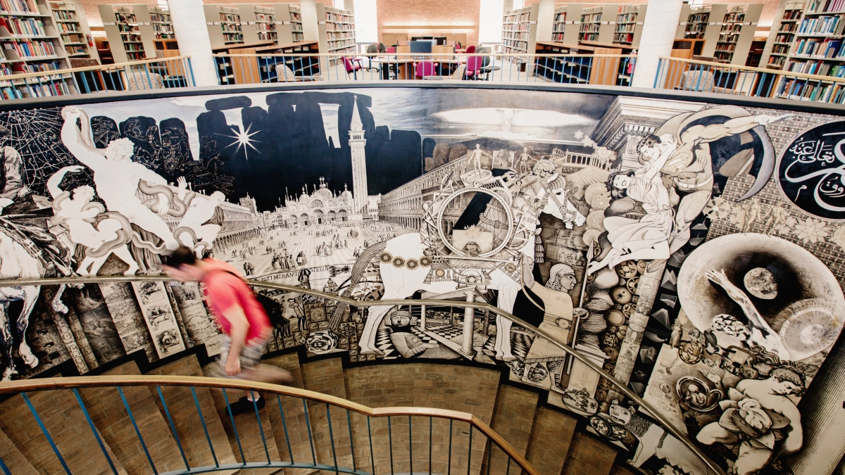 Student climbs spiral stairwell decorated with a mural in Coates Library