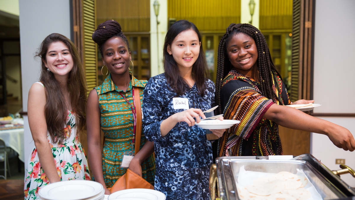 four women pose and smile during the international student reception in Chapman Great Hall