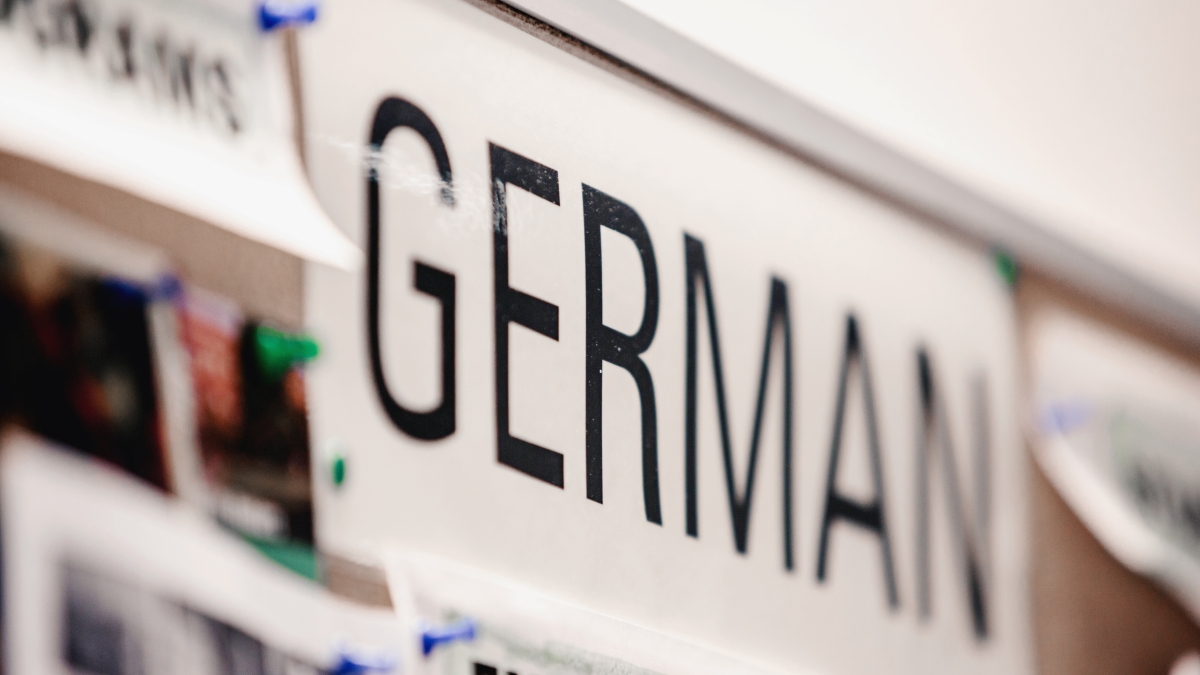 A sign with the word "German" pinned to tack board 