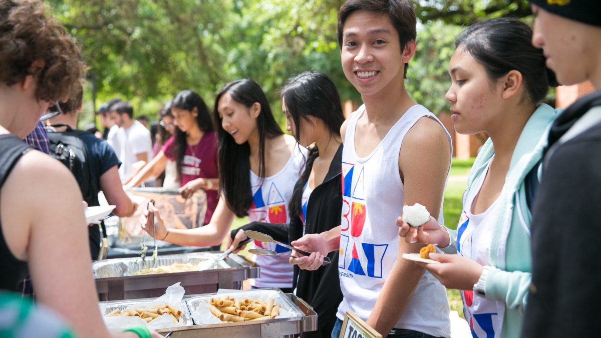 a male student serves food in line at Taste of Diversity