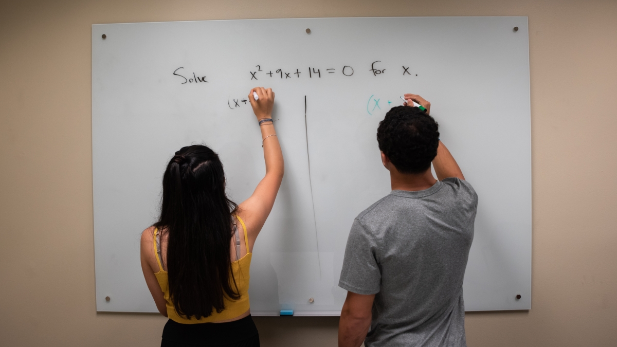 Two trinity students brainstorming on a whiteboard