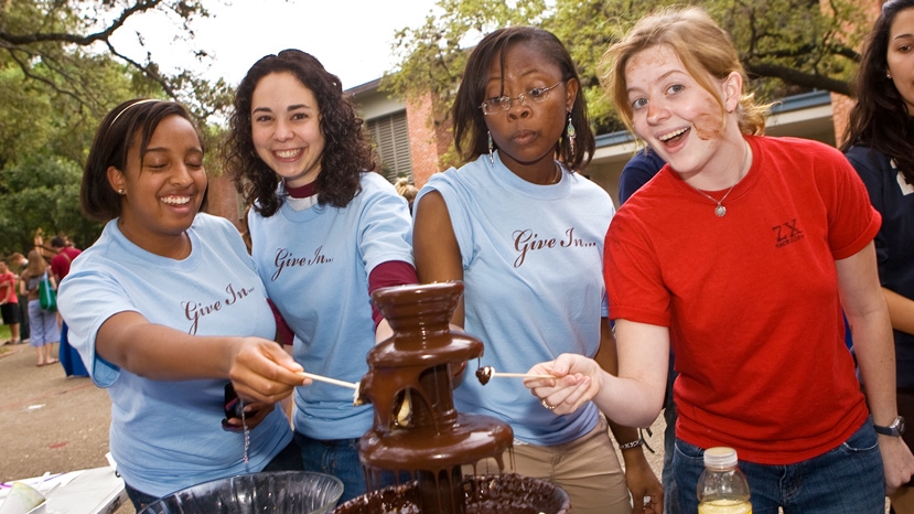 four women pose by a chocolate fountain
