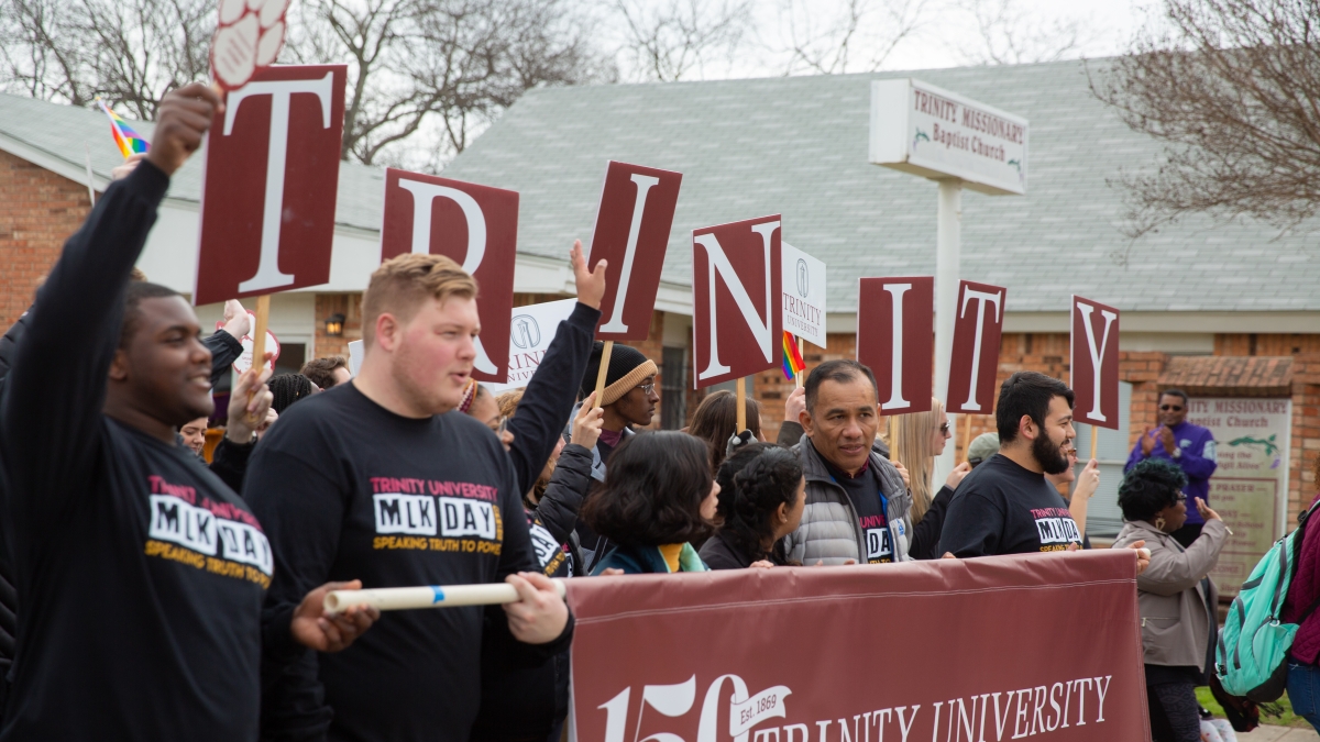 Group of people holding up a Trinity University 150th anniversary flag at MLK march