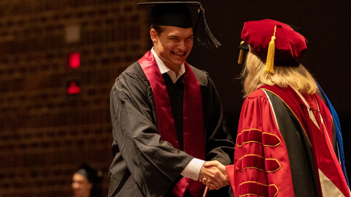 Student and faculty member shaking hands at commencement